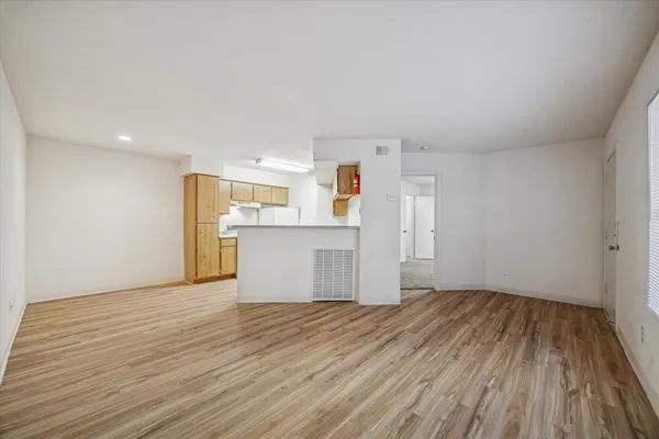 a view of a kitchen with wooden floor and white cabinets
