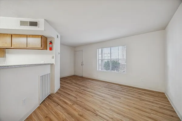 a view of an empty room with wooden floor and a window
