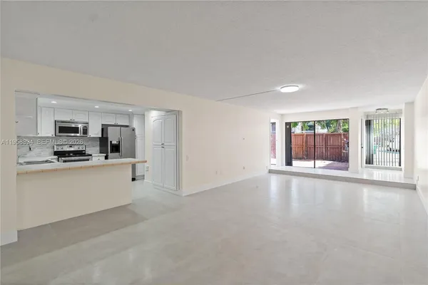 a large white kitchen with granite countertop a stove top oven a sink and white cabinets