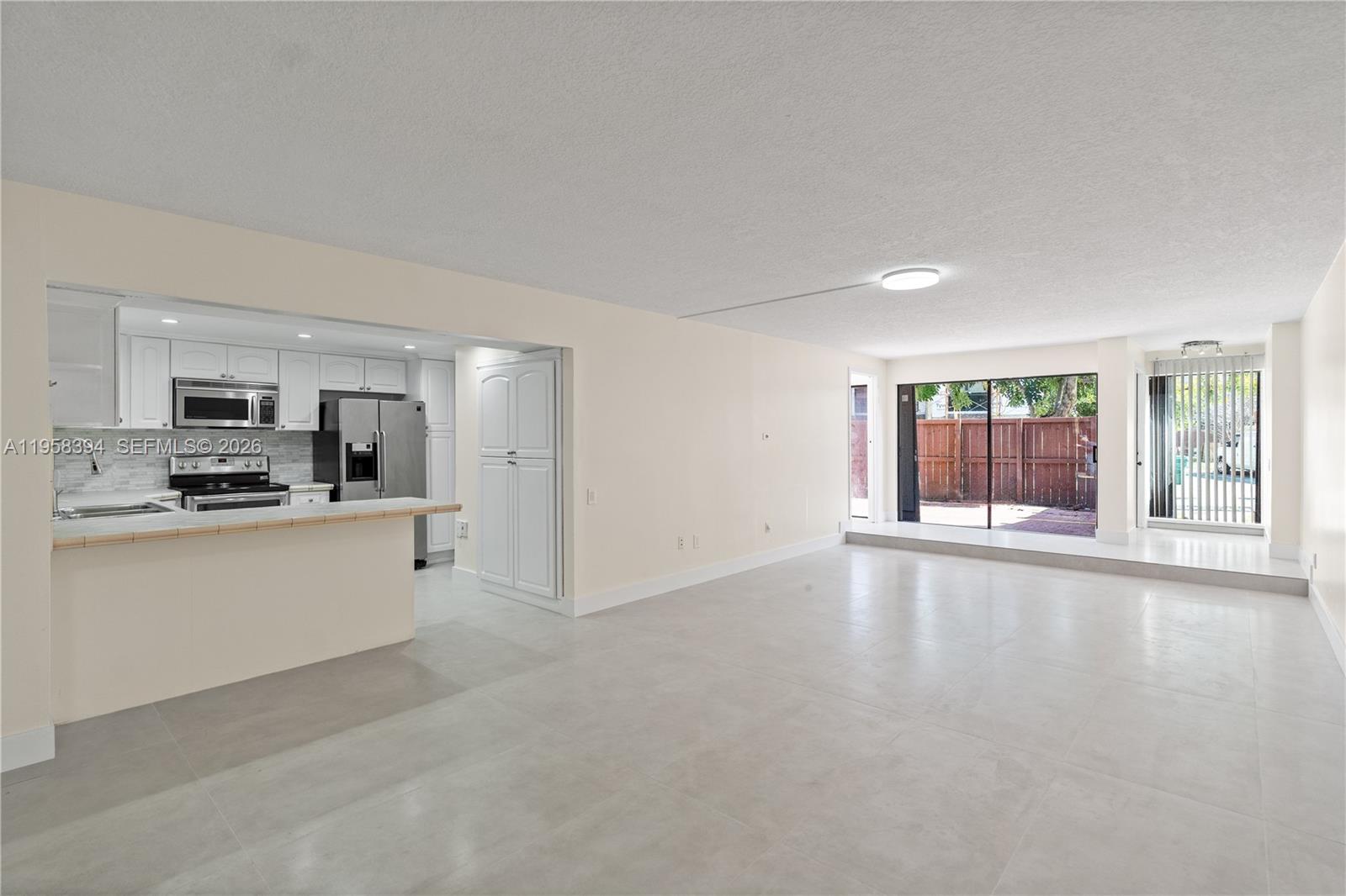 6907 Southwest 115th Place, Unit D40 Miami, FL 33173 - Photo 14 of 38 a large white kitchen with granite countertop a stove top oven a sink and white cabinets