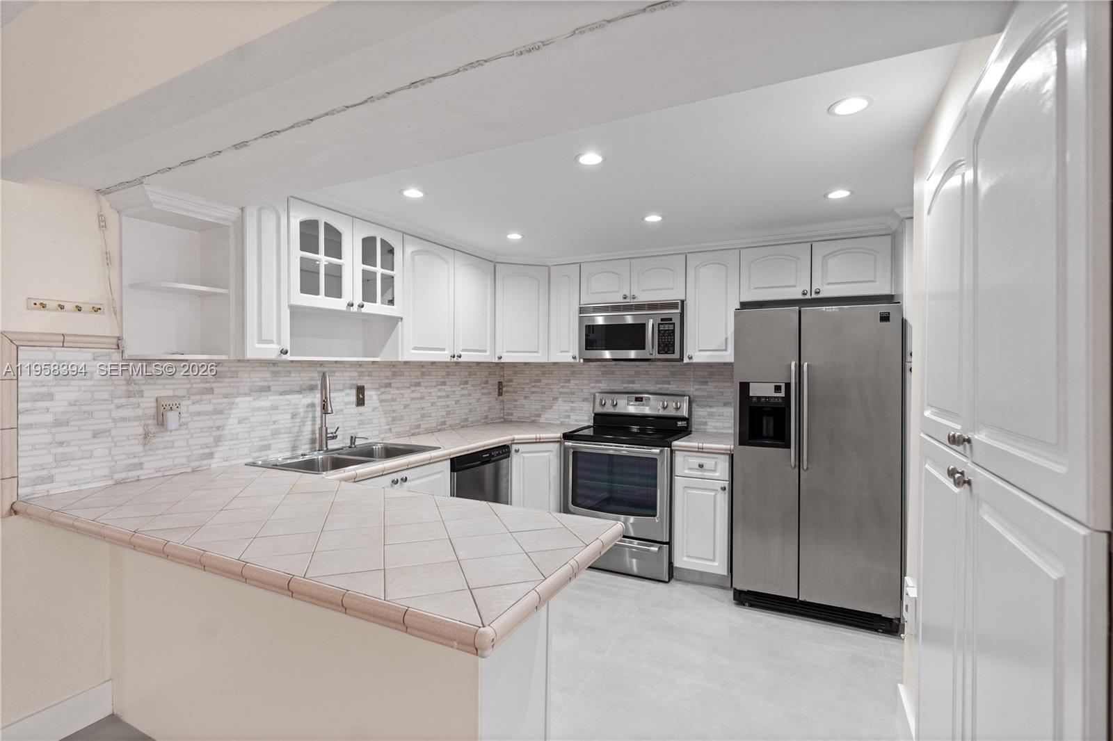 6907 Southwest 115th Place, Unit D40 Miami, FL 33173 - Photo 17 of 38 a kitchen with stainless steel appliances granite countertop a sink a stove a refrigerator and cabinets