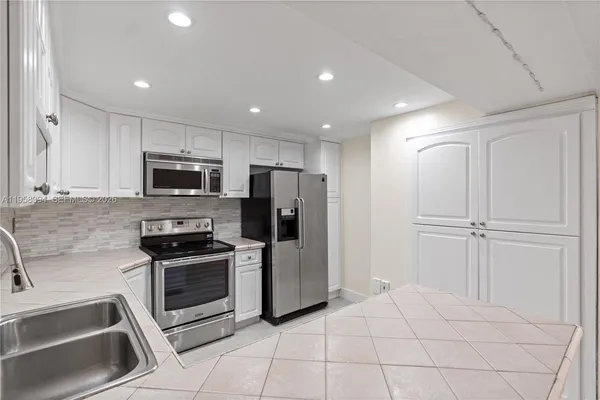 a kitchen with stainless steel appliances a refrigerator sink and microwave