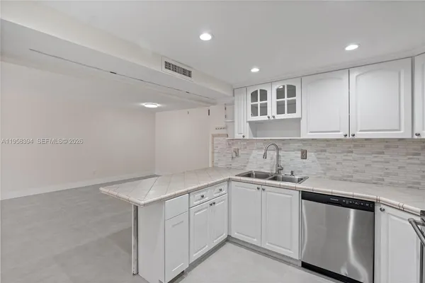 a kitchen with a sink dishwasher and white cabinets