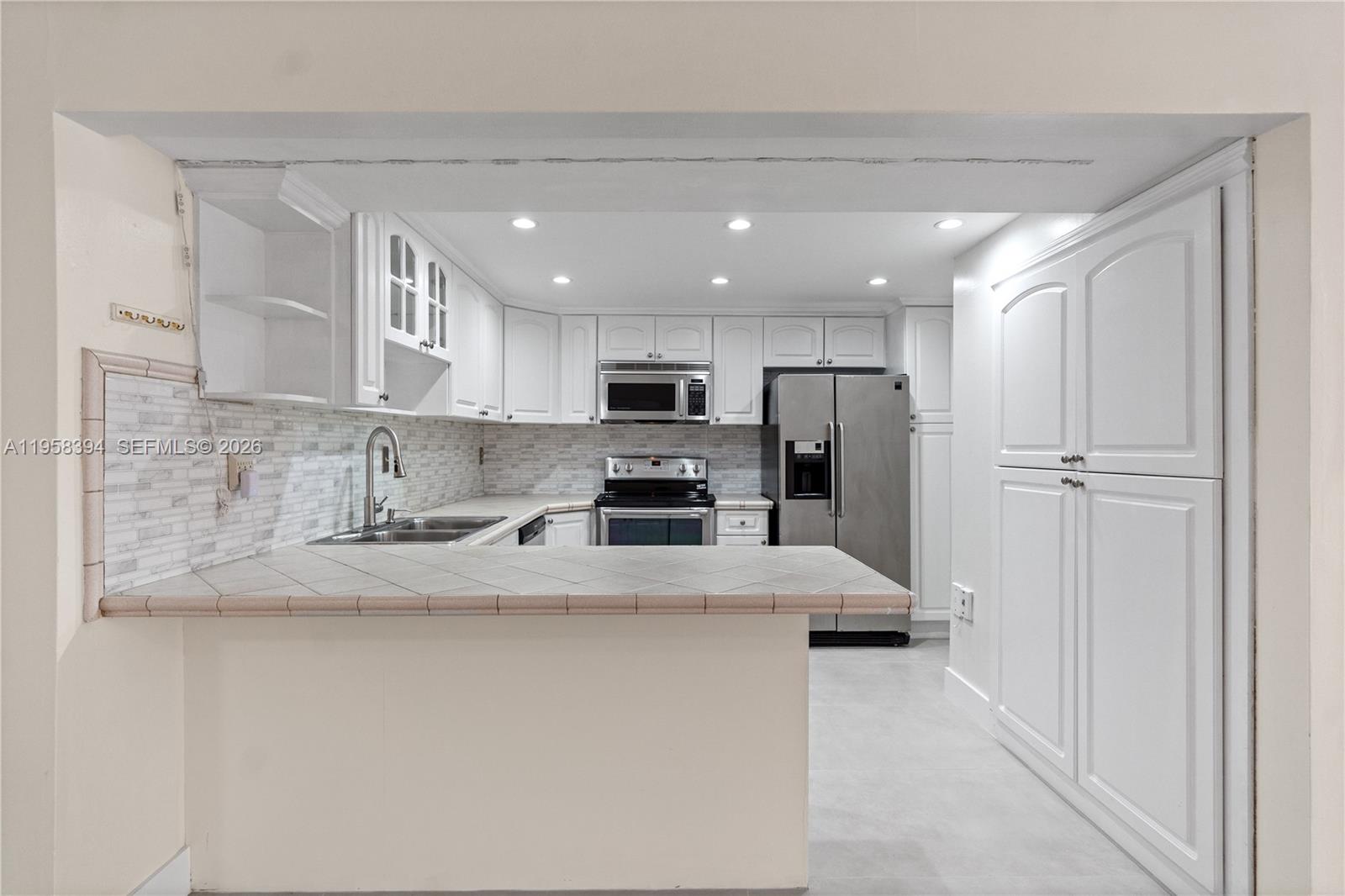 6907 Southwest 115th Place, Unit D40 Miami, FL 33173 - Photo 21 of 38 a kitchen with stainless steel appliances granite countertop a refrigerator sink and cabinets