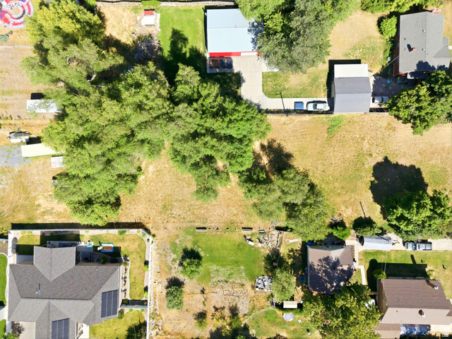 300 East S, Unit 2 Logan, UT 84321 - Photo 19 of 38 Expansive parcel featuring a large grassy area, mature trees, and existing structures including a building with a red roof and a gray-roofed structure