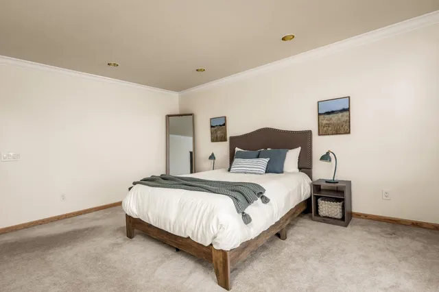 a spacious bedroom with a bed and a lamp on the dresser