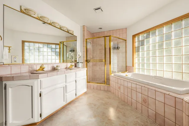 a spacious bathroom with a double vanity sink large mirror and a bathtub