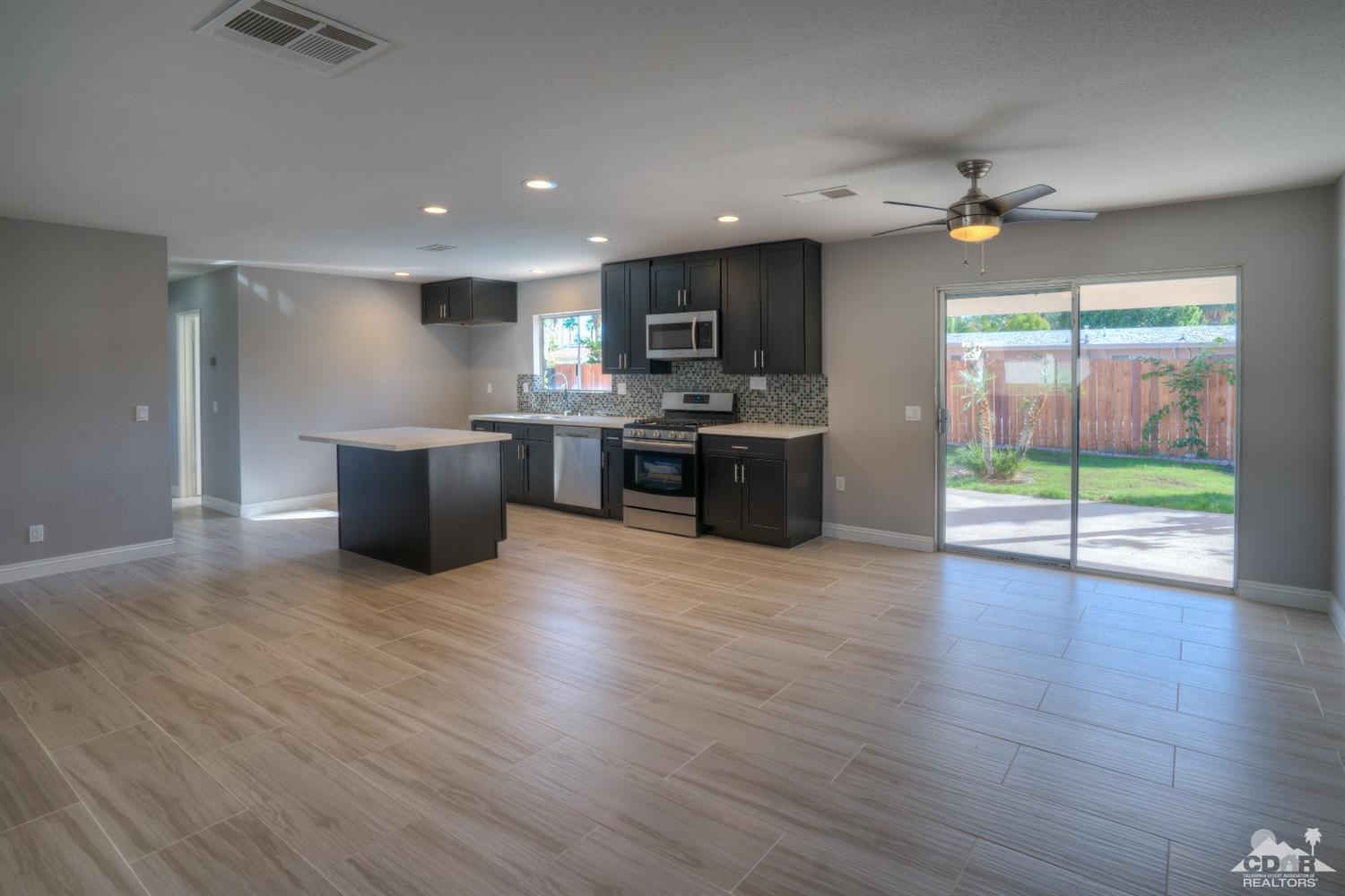 70121 Cobb Road Rancho Mirage, CA 92270 - Photo 6 of 15 an open kitchen with granite countertop a stove top oven a sink and dishwasher a dining table with wooden floor