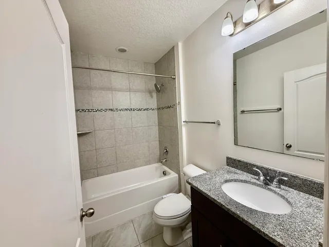 a bathroom with a granite countertop sink toilet mirror and bathtub
