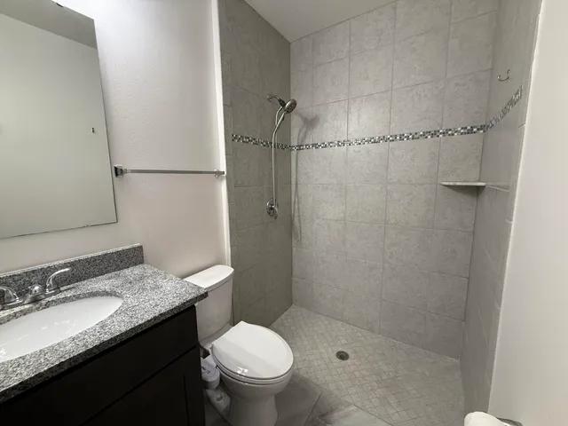 a bathroom with a granite countertop sink toilet and shower