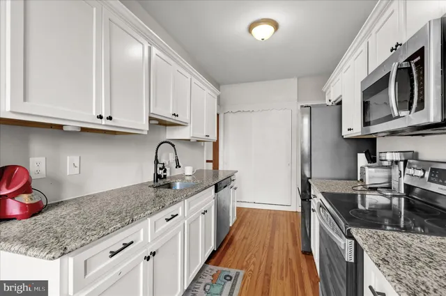 a kitchen with granite countertop a sink a stove and cabinets