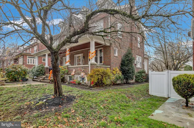 a view of a white house next to a yard with big trees