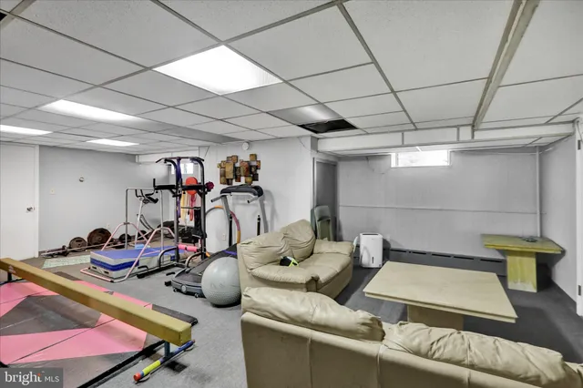 a living room with furniture a flat screen tv and gym equipment