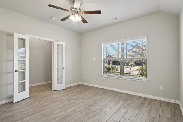 a view of an empty room with a window and wooden floor