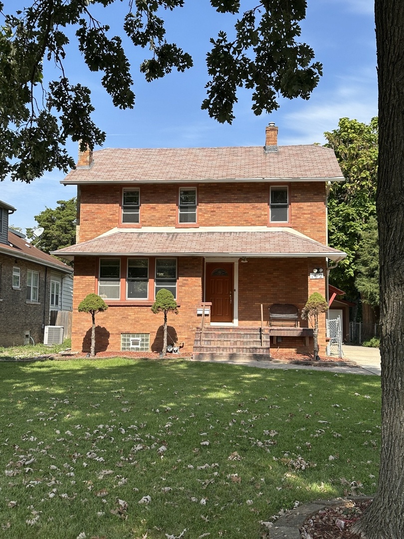 a front view of a house with a garden and trees
