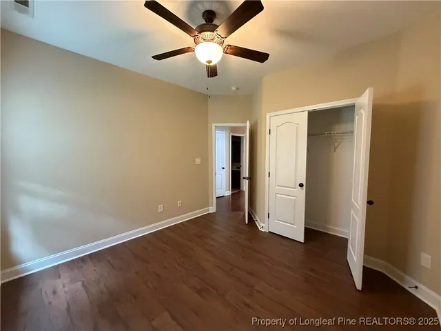 an empty room with wooden floor and a ceiling fan