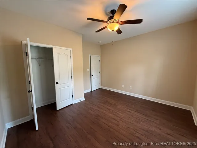 an empty room with wooden floor and a ceiling fan