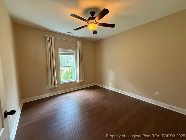 an empty room with wooden floor and ceiling fan