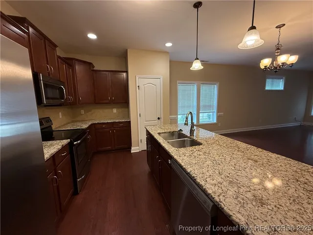 a kitchen with kitchen island granite countertop a sink appliances and cabinets