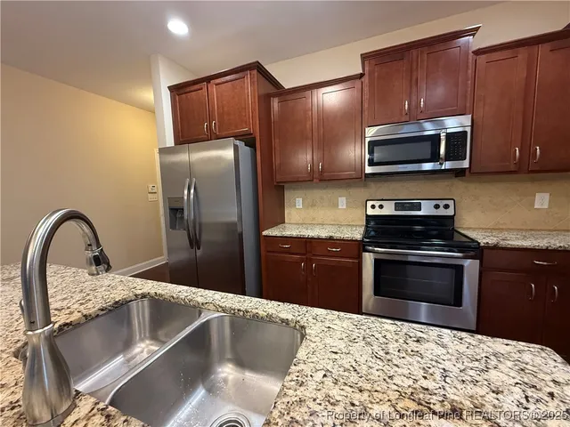a kitchen with stainless steel appliances granite countertop a refrigerator and a stove top oven