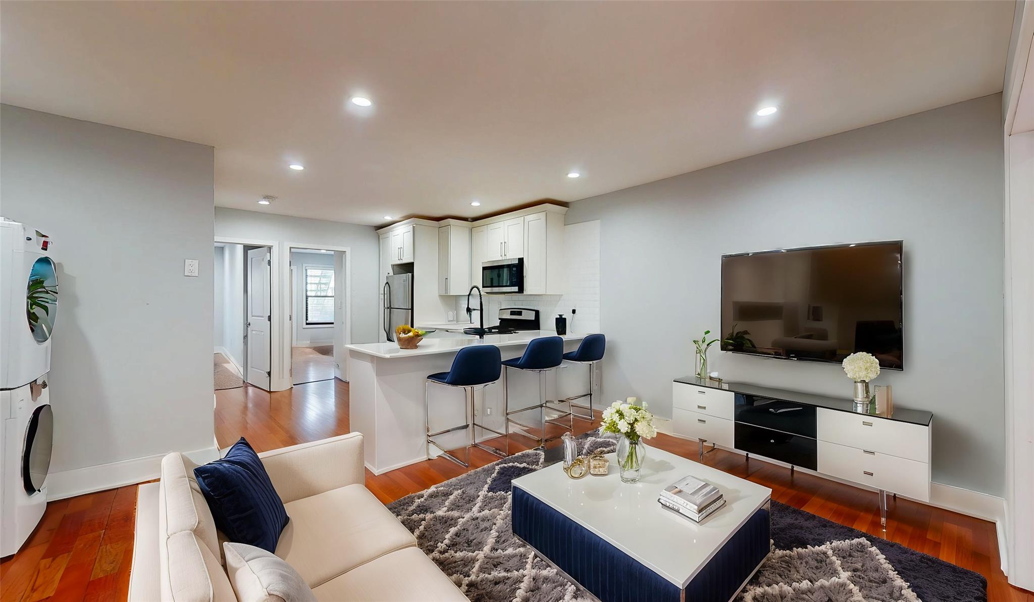 Living room featuring baseboards, recessed lighting, stacked washing maching and dryer, and wood finished floors