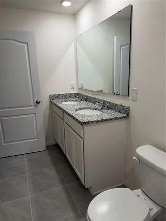 a bathroom with a granite countertop toilet sink and mirror