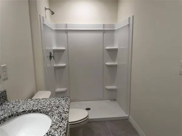 a bathroom with a granite countertop sink a toilet and shower