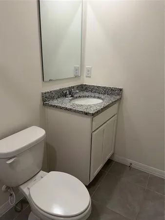 a bathroom with a granite countertop toilet and a sink