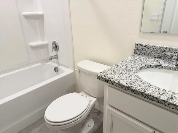 a bathroom with a granite countertop toilet sink and mirror