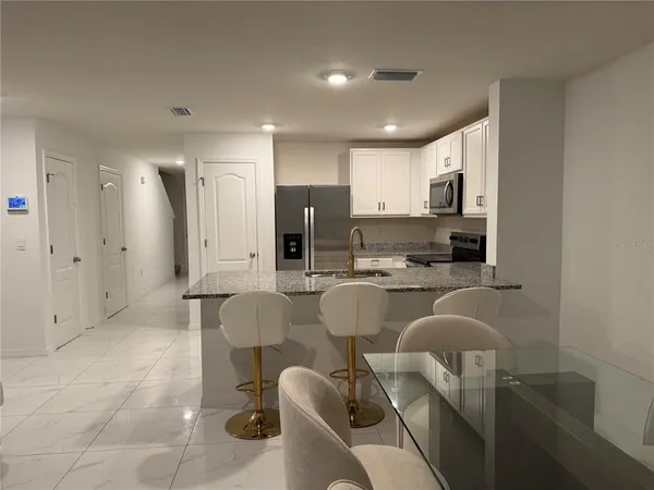 a large white kitchen with lots of counter space dining table and chairs