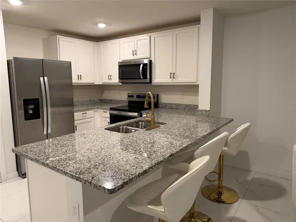 a kitchen with stainless steel appliances granite countertop a sink and a refrigerator