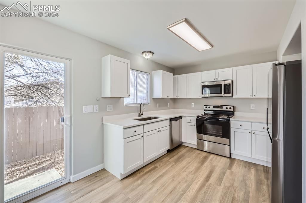 359 Ellers Grove Colorado Springs, CO 80916 - Photo 7 of 27 Kitchen featuring white cabinetry, sink, and stainless steel appliances