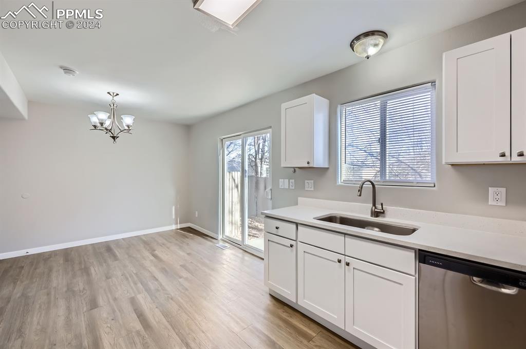 359 Ellers Grove Colorado Springs, CO 80916 - Photo 9 of 27 Kitchen with white cabinetry, sink, stainless steel dishwasher, and light wood-type flooring