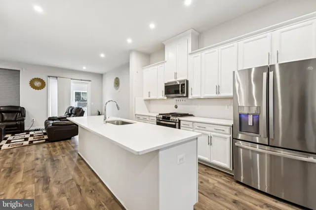 a large white kitchen with a refrigerator a stove a sink dishwasher and a stove with wooden floor