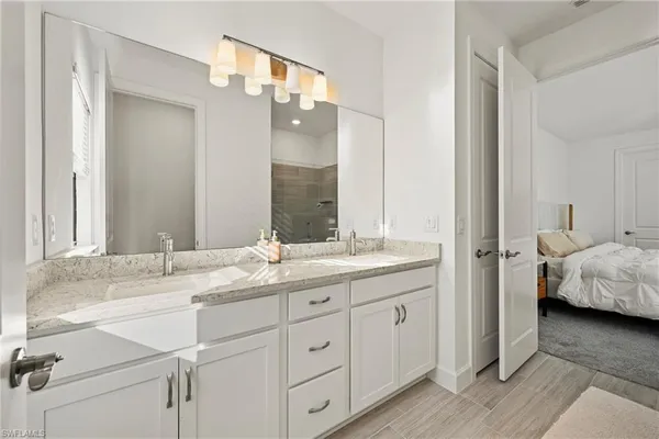 a en suite bathroom with a granite countertop double vanity sink and a mirror