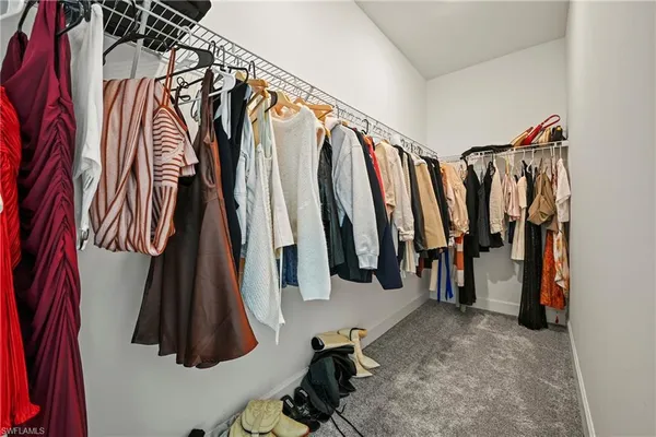 a view of walk in closet with clothes and shoes