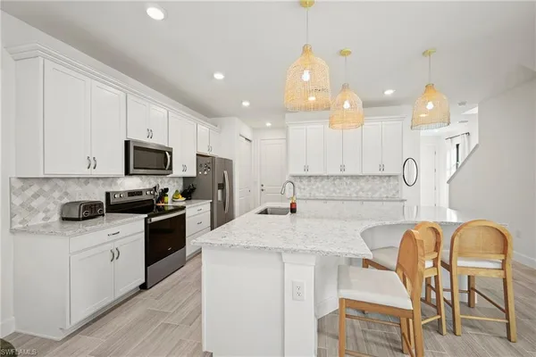 a kitchen with stainless steel appliances granite countertop a stove top oven a sink a dining table and chairs with wooden floor