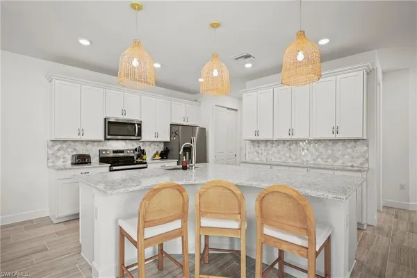 a kitchen with stainless steel appliances granite countertop a sink a stove a refrigerator cabinets and chairs