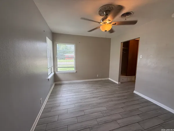 a view of an empty room with wooden floor and a window