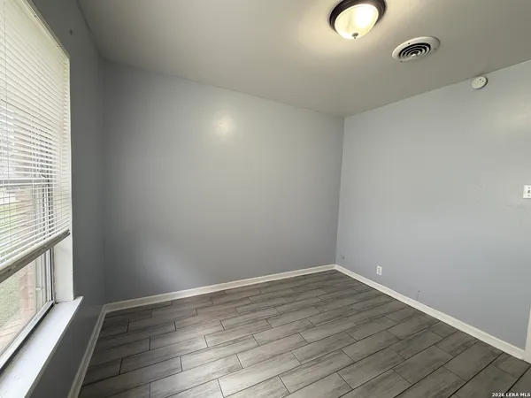a view of an empty room with wooden floor and a window