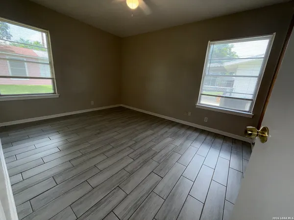 an empty room with wooden floor and windows
