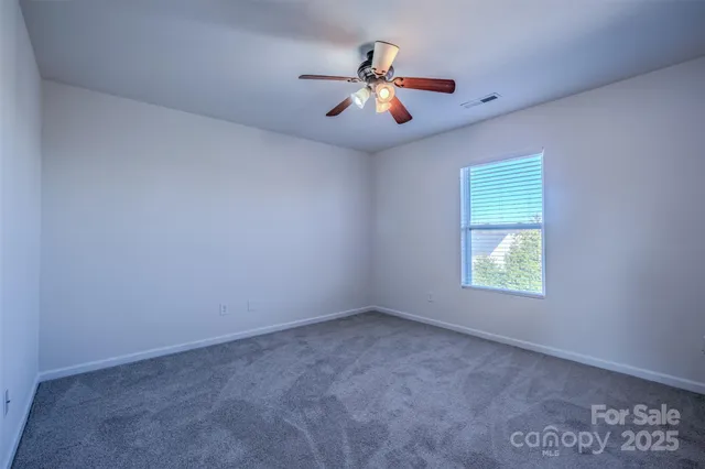an empty room with ceiling fan and window