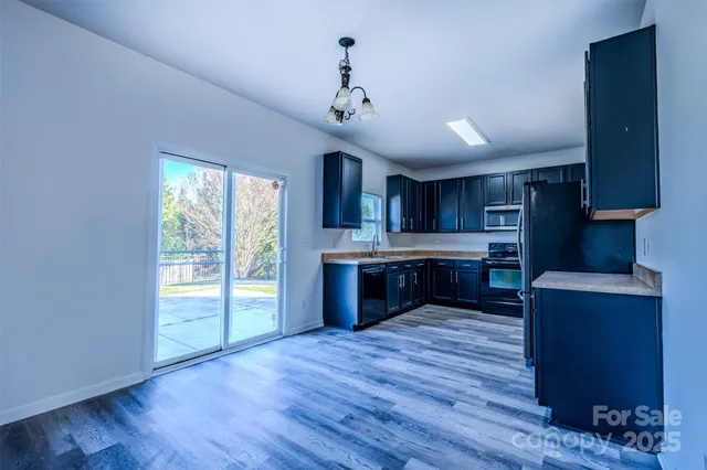 a large kitchen with stainless steel appliances granite countertop a stove and a wooden floors