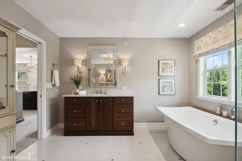 a spacious bathroom with a tub sink and mirror