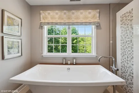 a white bath tub sitting in a bathroom next to a window