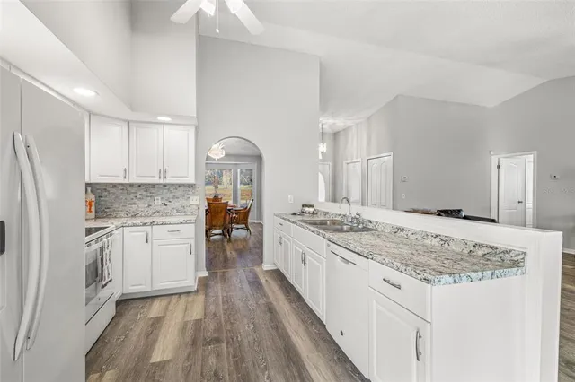 a kitchen with granite countertop a sink stove and refrigerator