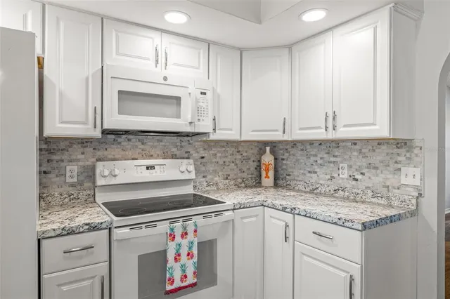 a kitchen with granite countertop a sink stove and cabinets