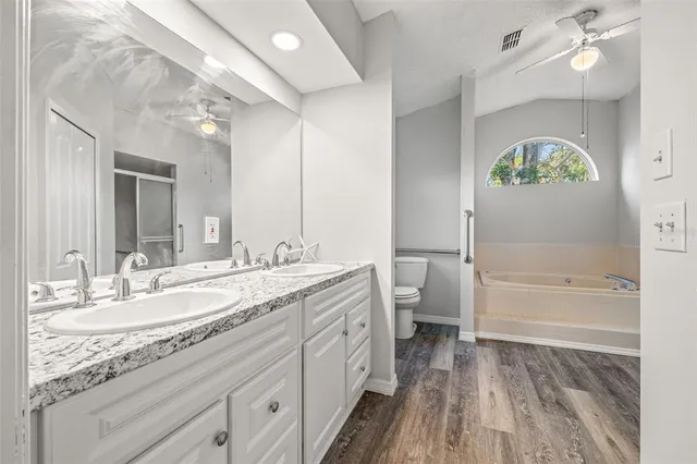 a spacious bathroom with a granite countertop sink a toilet a mirror and shower