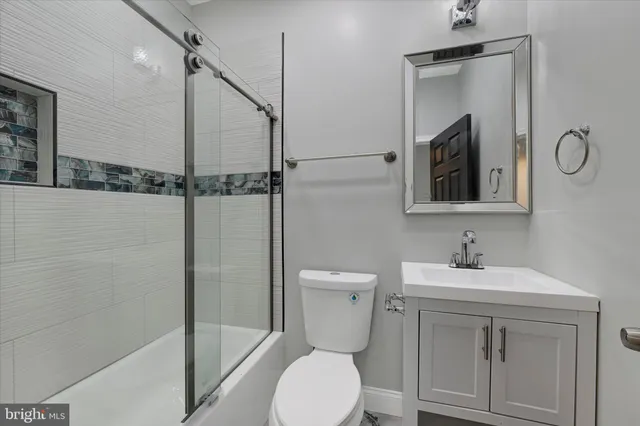 a bathroom with a toilet sink vanity granite and shower