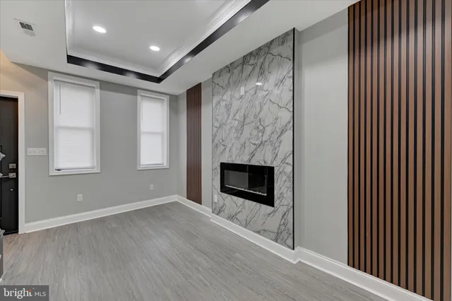 a view of an empty room with wooden floor fireplace and a window